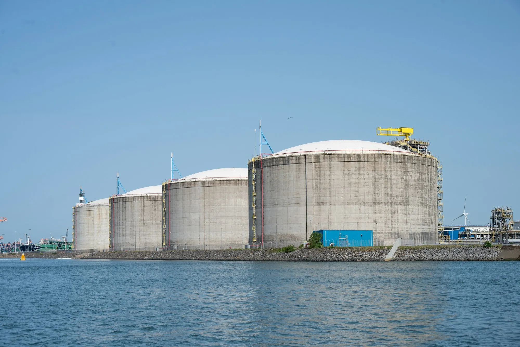 LNG storage tanks on the waterfront under a clear sky